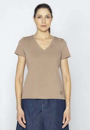 Beżowa koszulka typu V-neck, wykonana z miękkiego materiału, z krótkimi rękawami i zaokrąglonym dołem. Posiada małe logo w prawym dolnym rogu. Prosty design.