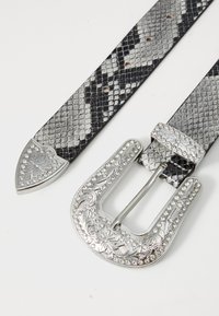 Ceinture en cuir noir et gris à motif serpent avec une large boucle en argent ornée de strass et de détails floraux gravés.