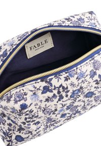 Pučka sa floralnim uzorkom s plavim i bijelim cvjetovima, vidljivim unutarnjim oznakom "FABLE England" i zlatnim zipom.