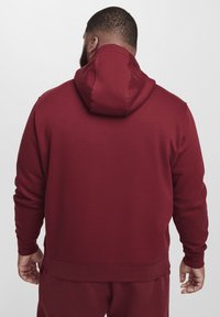 Bordeaux hoodie met een zachte textuur, geribbelde manchetten en een tailleband. Heeft een ontspannen pasvorm met een grote kap aan de achterkant.