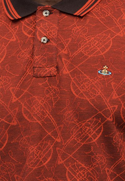 Κόκκινο πόλο με μαύρο γιακά και πορτοκαλί ρίγες, με τονικό μοτίβο μουσικού οργάνου και μικρό κεντητό λογότυπο πλοίου στο στήθος.