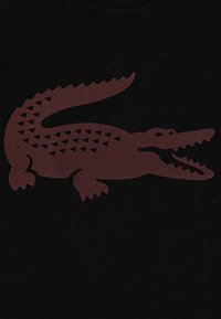 Tissu noir avec un grand motif de crocodile bordeaux et un motif de triangle texturé le long de son corps.