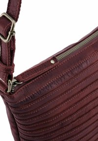 Borsa a spalla in pelle bordeaux con un design a trama trapuntata, dotata di una cerniera argentata e di una chiusura in metallo. Dettaglio del logo impresso visibile.