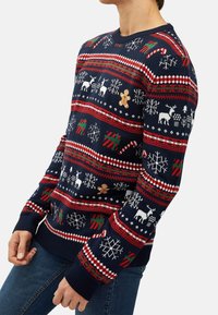 Navy blue knitted sweater featuring a holiday pattern of reindeer, snowflakes, and gingerbread, with red and green accents and ribbed cuffs.