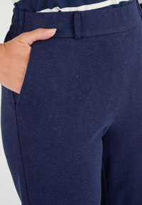 Pantaloni blu navy realizzati in tessuto morbido, con vita elasticizzata e tasche laterali. Il capo ha una texture liscia e un design informale.