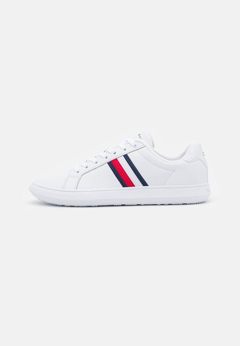 Bílé sneakers s hladkým syntetickým materiálem, na boku se vzory v červené a námořnické modři a s texturovanou gumovou podrážkou.