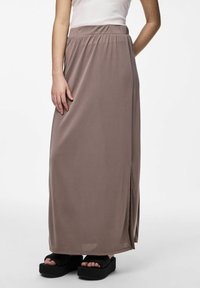 Lång, taupe maxi kjol gjord av mjukt tyg med elastisk midja och en sidssprund. Matchad med svarta plattformsandaler.