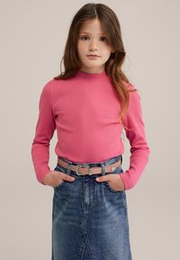 Rosa långärmad ribbad topp som matchas med en denimkjol med en centrerad söm och ett ljust rosa bälte med dekorativa metalldetaljer.