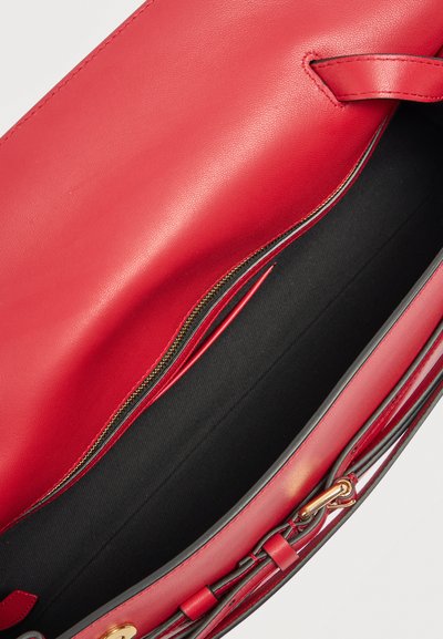 Τσάντα χειρός από κόκκινο δέρμα με μαύρο ύφασμα εσωτερικά, χρυσή τσέπη με φερμουάρ και διακοσμητικό λουράκι στο πλάι.