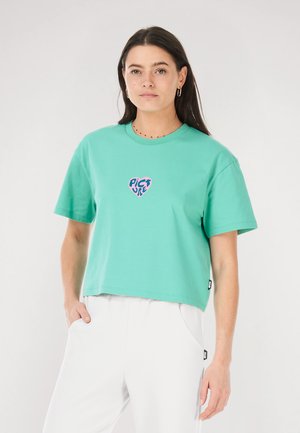Light green cropped t-shirt made from cotton with short sleeves. Features a heart-shaped logo in pink and blue at the center.