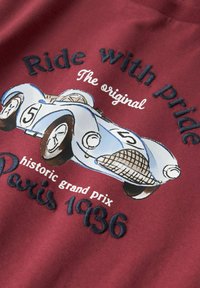 Grafik mit einem hellblauen Vintage-Rennwagen, Nummer 5, auf einem bordeauxfarbenen Stoff gestickt, mit dem Text: "Fahre mit Stolz" und "Paris 1936."