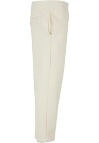 White cotton sweatpants with an elastic waistband, side pockets, and a smooth texture. The design features clean lines and a tapered leg.