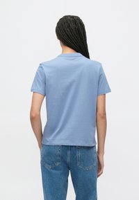 Blå bomull T-skjorte med rund hals og korte ermer, med glatt tekstur og avslappet passform. Brukt sammen med denimjeans.