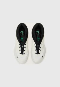 Scarpe da ginnastica bianche e nere con una superficie liscia, caratterizzate da accentuazioni verdi, un'area dei lacci testurizzata e un design a punta arrotondata.