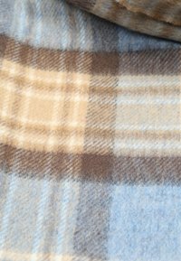 Geruite deken met zacht, geborsteld materiaal in beige, blauw en bruine tinten, met een ruitpatroon en een pluizige textuur.