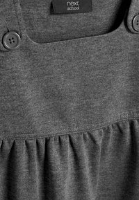 Graues Baumwollkleid mit Knopfdetails, das einen gerafften Taillenbund und eine glatte Textur aufweist, beschriftet mit "nächste Schule."