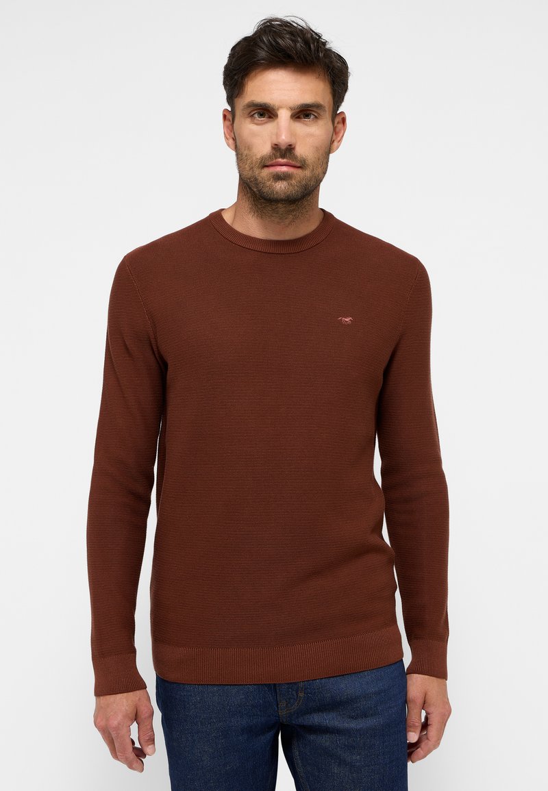 Brauner Strickpullover mit rundem Ausschnitt, gerippten Bündchen und Saum. Verfügt über eine dezente Logo-Applikation auf der Brust. Wird mit blauen Jeans getragen.