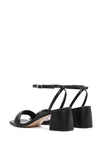 Sandales noires à talons avec une finition en cuir lisse, design à bout ouvert, fines lanières à la cheville et un talon épais.