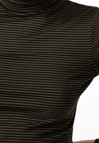 Tight passande polokrage topp gjord av stretchy tyg med smala svarta och olivgröna horisontella ränder. Slät textur med lätt glans.