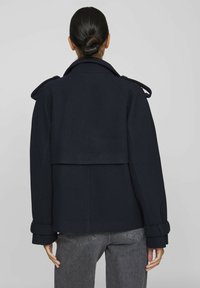 Marinblå ullmixkappa med dubbelknäppning, bred krage, axelplymer och långa ärmar med manschettdetaljer.
