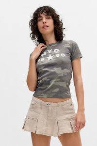 T-shirt à manches courtes gris camouflage avec texte blanc "NYC 1990" et étoile ; associé à une jupe mini plissée beige avec poches avant et bouton.