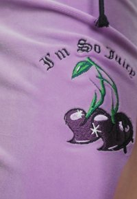 Violets audums audums ar izšūtām ķiršiem un zaļām lapām, ar tekstu "Es esmu tik sulīgs" treknā fontā virs dizaina.
