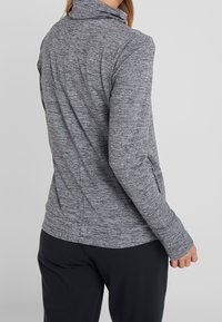Grau strukturierte Zip-Jacke mit hohem Kragen und langen Ärmeln, mit Seitentaschen und taillierter Passform.