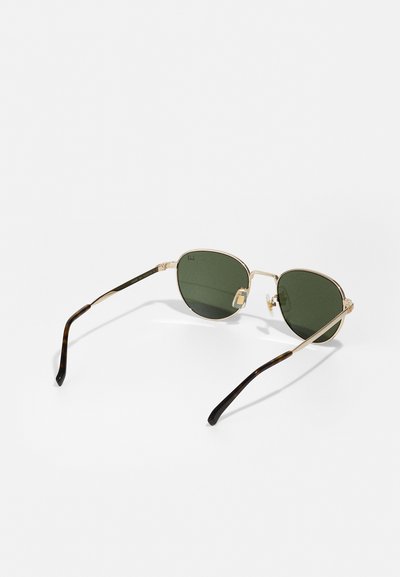 Lunettes de soleil en doré avec des verres verts, en forme de goutte d'eau, présentant un motif écaille sur les branches et des accents en métal à l'avant.