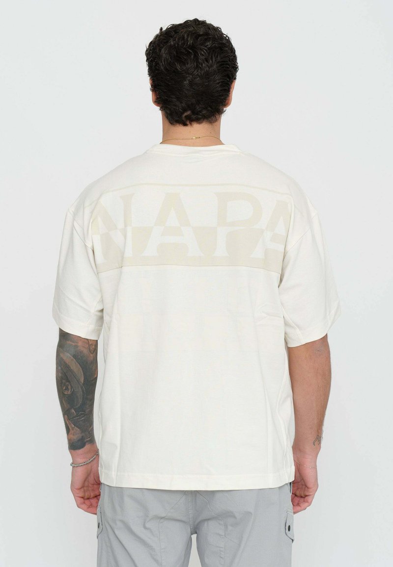 T-shirt a maniche corte color crema con grande scritta "NAPA" sbiadita sul retro. Realizzato in tessuto morbido con una vestibilità rilassata.