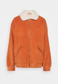 Veste en velours côtelé orange avec un col en fourrure crème. Dotée d'une fermeture éclair à l'avant, de deux poches latérales, et de poignets et ourlet côtelés. Surface texturée.