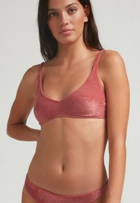 Conjunto de bralette y braguitas acolchado en color rosa metálico. Tela suave y texturizada con tirantes delgados y un diseño minimalista.