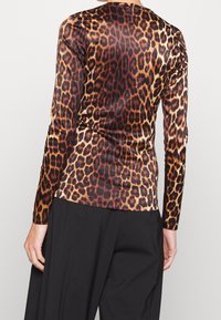 Långärmad topp i slät tyg med ett djärvt leopardmönster i brunt, svart och beige, med en figurnära passform och rund halsringning.