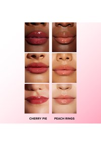 Échantillons de baume à lèvres affichés en deux rangées avec diverses teintes : rouge rose foncé, rose clair, et finitions brillantes. Les étiquettes indiquent "Cherry Pie" et "Peach Rings."