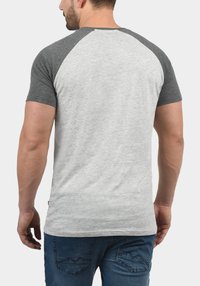 Szara i jasnoszara koszulka z krótkim rękawem typu raglan, wykonana z mieszanki bawełny, o dopasowanym fasonie i gładkiej fakturze.