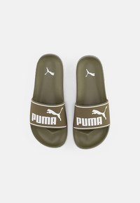 Olivgröna slidesandaler med ett strukturerat rem som har en vit "PUMA"-logotyp och små logotypdetaljer. Platt och öppen tådesign.