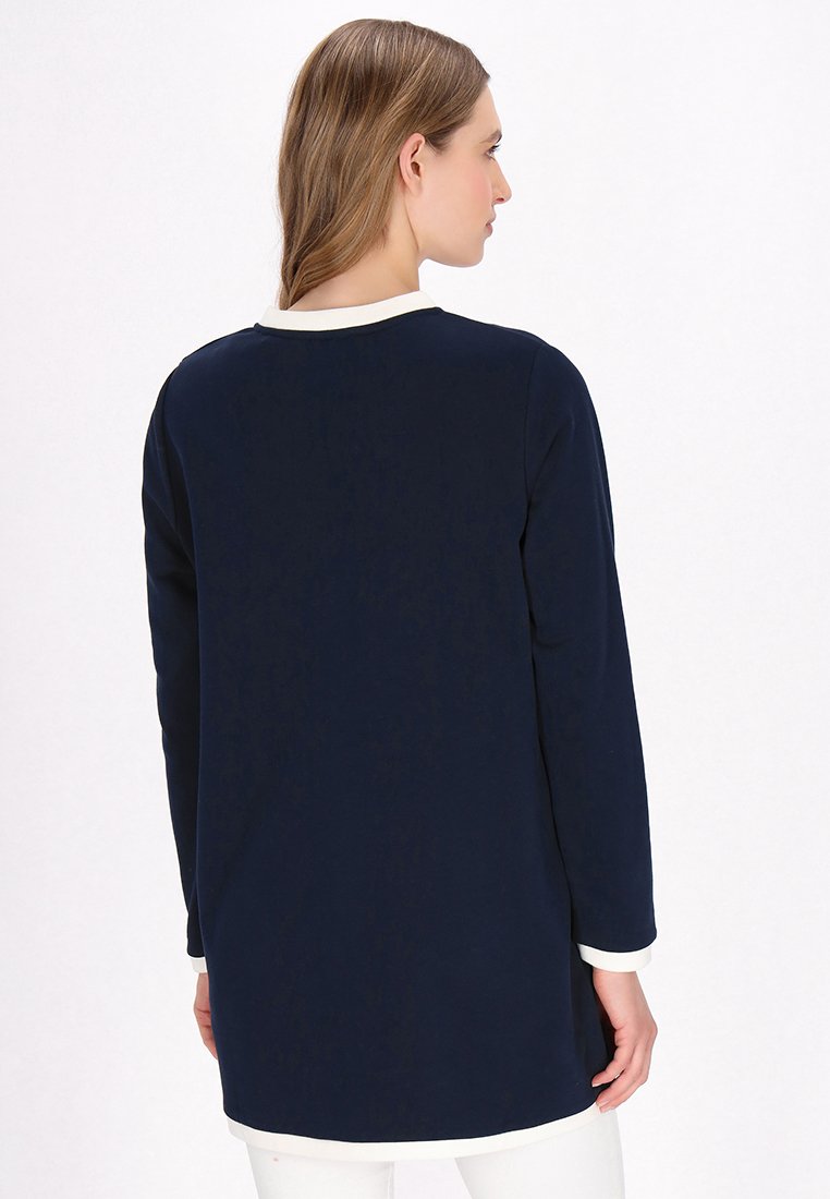 Marineblauwe tuniek met lange mouwen en een ronde halslijn, voorzien van witte bies langs de kraag en mouwen, met een gladde textuur en een relaxte pasvorm.