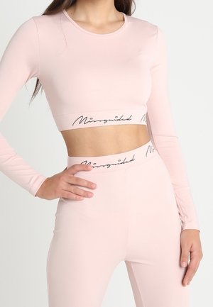 Jasnoróżowy długi rękaw crop top o dopasowanym kroju, z markowym paskiem na dole. Gładka tekstura, w zestawie z pasującymi spodniami o wysokim stanie.