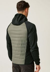 Kapuzenshirt mit einer schwarzen Vorderseite, grünem, gestepptem Rücken und strukturiertem Stoff. Verfügt über ein tailliertes Design und kontrastierende Farbblöcke.