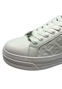 Sneaker bianca con pelle liscia, motivo testurizzato sui lati, punta rotonda, lacci piatti e dettagli metallici nei passanti.