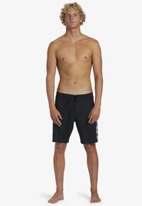Bañador negro con cintura elástica, presenta un patrón floral en los lados. Fabricado con material ligero y de secado rápido.