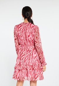 Rochie roz cu un model cu dungi de zebră, mâneci lungi, tiv fetițat, talie strânsă, realizată dintr-un material ușor.