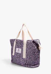 Lepardikuvioinen olkalaukku purppurakankaasta, jossa on vaaleat hihnat ja pääkallo logo valkoisella tarralla. Varustettu turvallisella napilla.