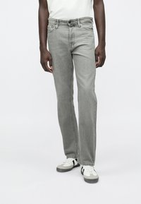 Jeans din denim gri cu croială dreaptă, design cu cinci buzunare și decolorare subtilă. Asortați cu adidași albi și gri.