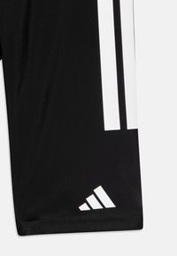 Shorts de sport noirs avec des rayures verticales blanches et un logo Adidas blanc près de l'ourlet. Tissu lisse avec une coupe ajustée.
