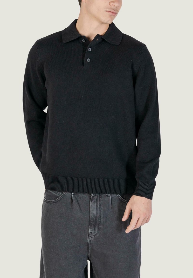 Pullover nero a maglia con colletto strutturato, patta con tre bottoni e polsini e orlo a coste. Realizzato in materiale morbido e testurizzato.