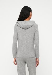 Sweatshirt cinza com capuz, feito de tecido suave, apresentando mangas longas, um corte descontraído e uma barra curva. A vista traseira mostra um design simples sem embellishments.