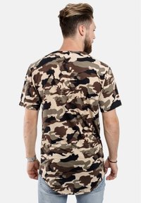Kortärmad, kamouflage t-shirt i beige, brun och svart. Mjuk textur, avslappnad passform, rundad nederkant och subtil detalj med söm på baksidan.