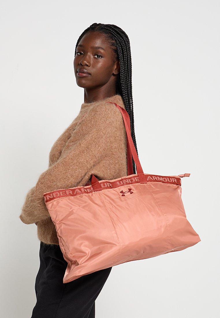 Bolsa de tote de nylon rosa con asas rojas y marca, que cuenta con un amplio compartimento principal y una textura suave y brillante.