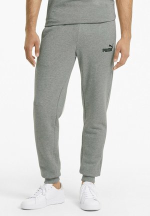 Pantalones de chándal grises hechos de una tela suave con piernas ajustadas, con un logo negro de Puma en el muslo izquierdo y puños acanalados. Llevados con zapatillas blancas.