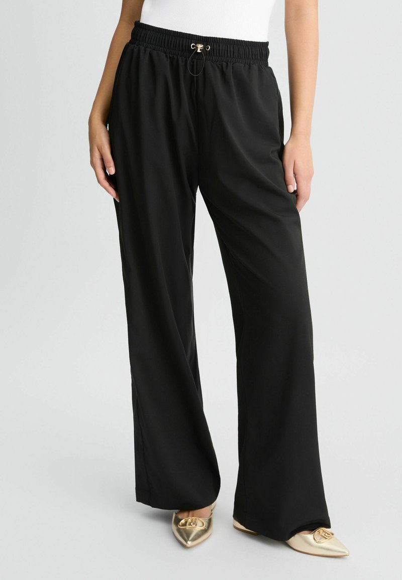 Zwarte wijde broek met een elastische tailleband en trekkoord. De stof is soepel en lichtgewicht, aangevuld met goudkleurige hardware.